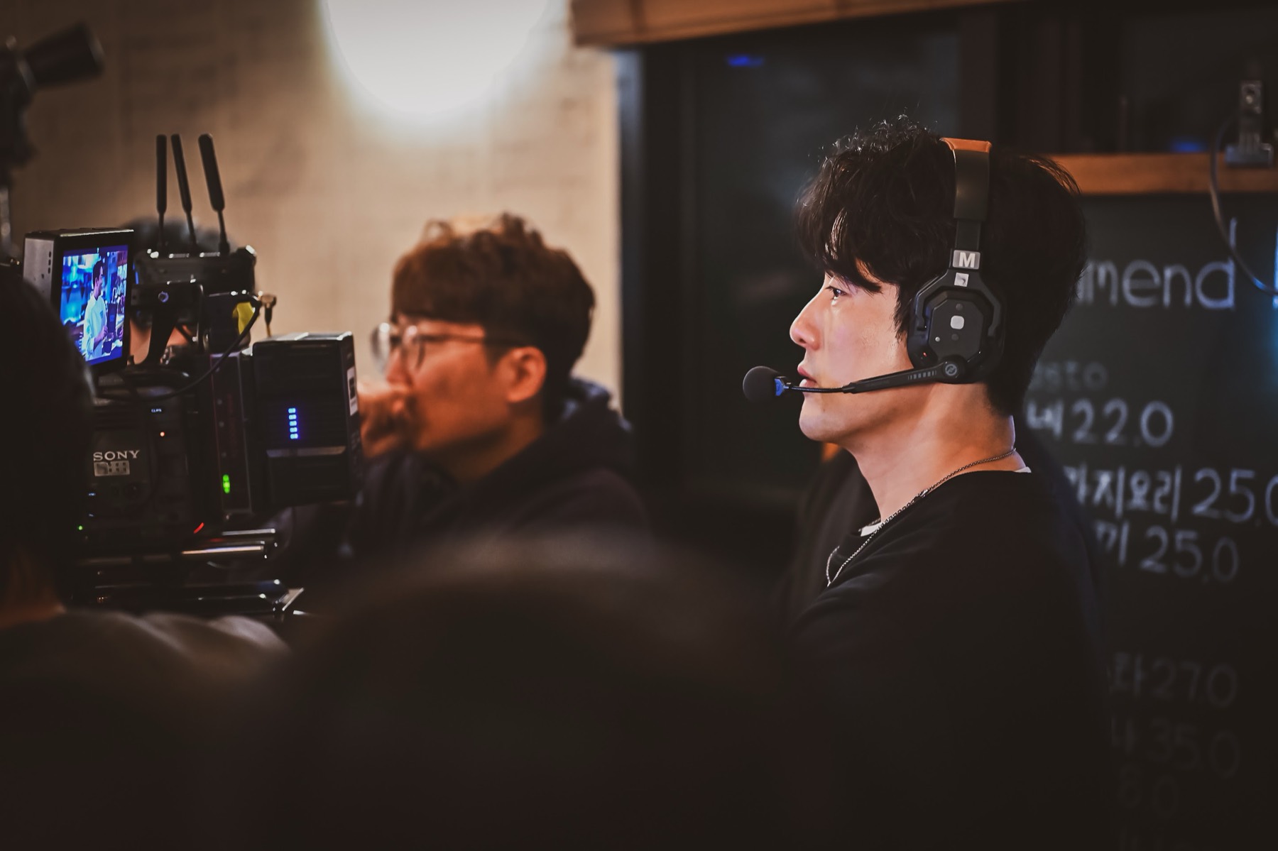 헤드셋을 쓴 감독이 모니터 앞에서 화면을 확인하는 모습